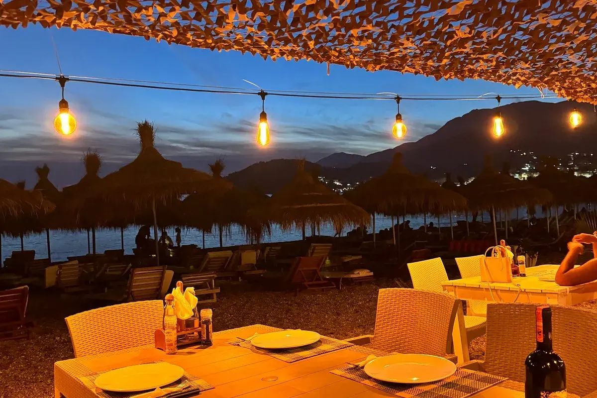 Wooden beachfront pergola with set tables at sunset at Lui Potam on Potam Beach in Himara