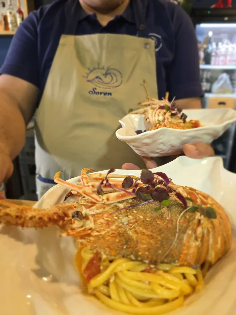 Plated lobster pasta served by staff in a branded Soren apron at Soren Restaurant in Himara
