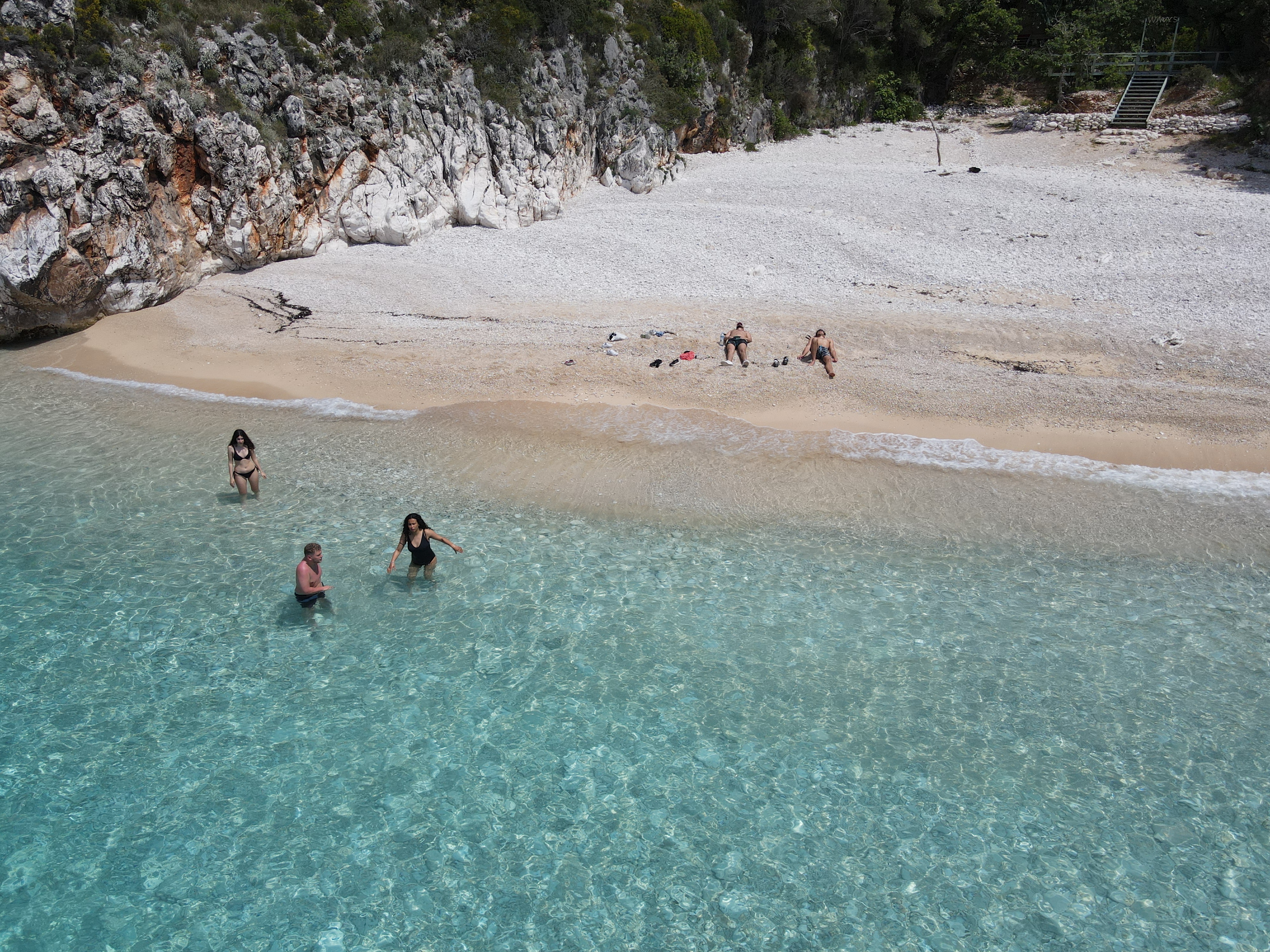 Aerial view of swimmers in clear shallow water at a Himara beach