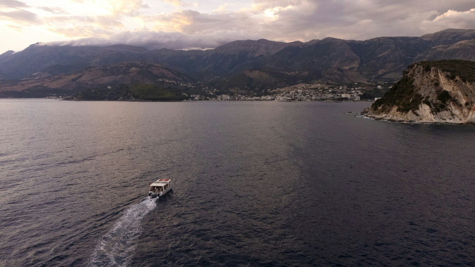 Boat approaching Himara at dusk with Ceraunian Mountains in the background
