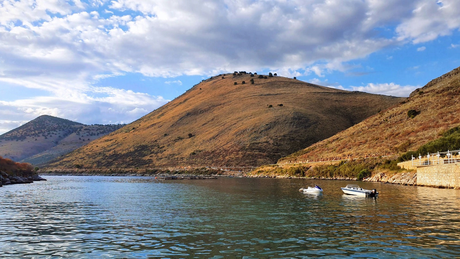 Golden evening light over Himara bay with a boat on calm waters