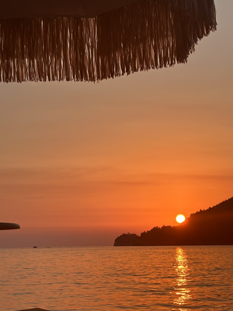 Ocean horizon with orange winter sunset sky near Himara