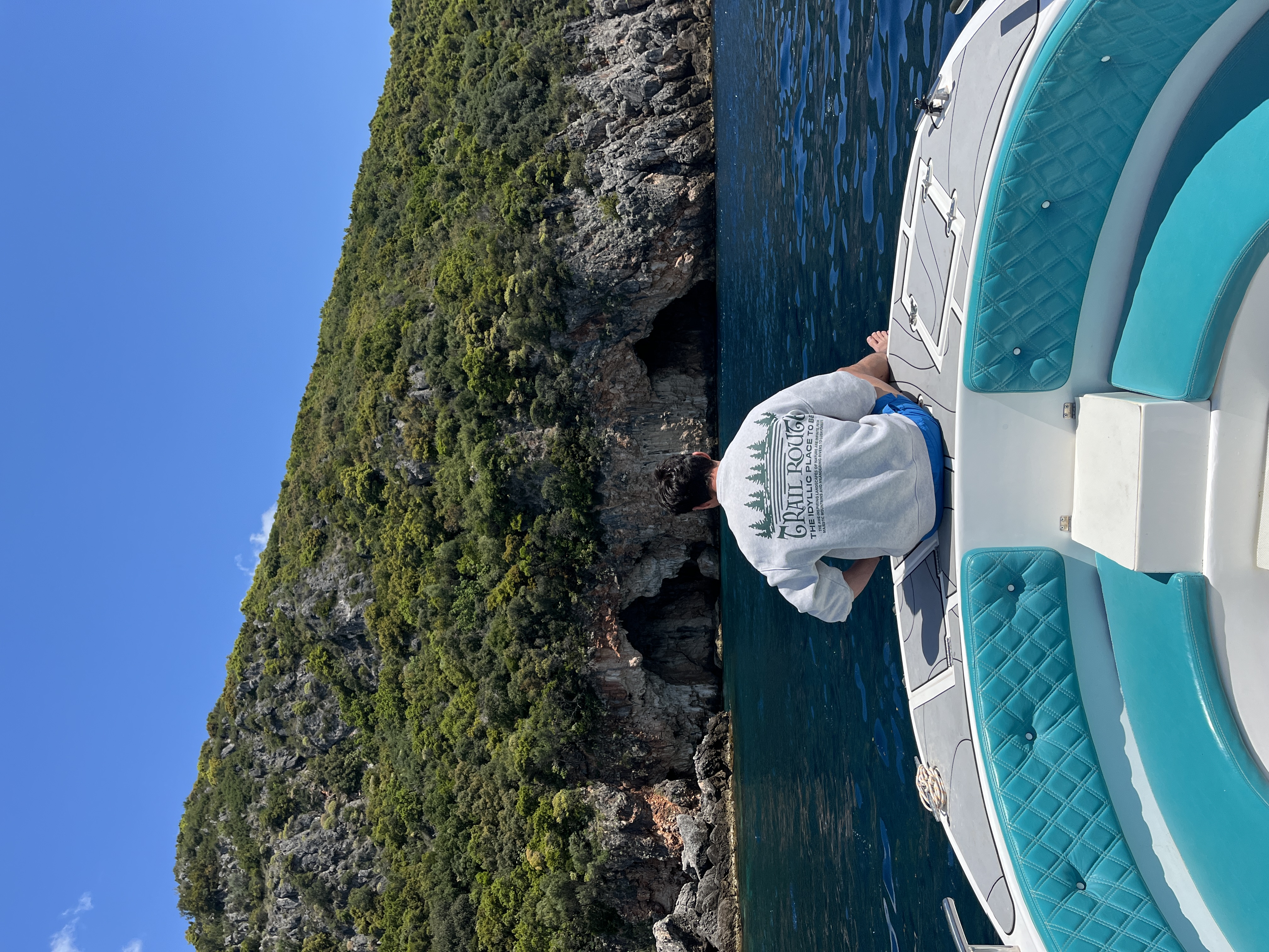 Boat approaching a hidden turquoise cove along the coastline near Himara