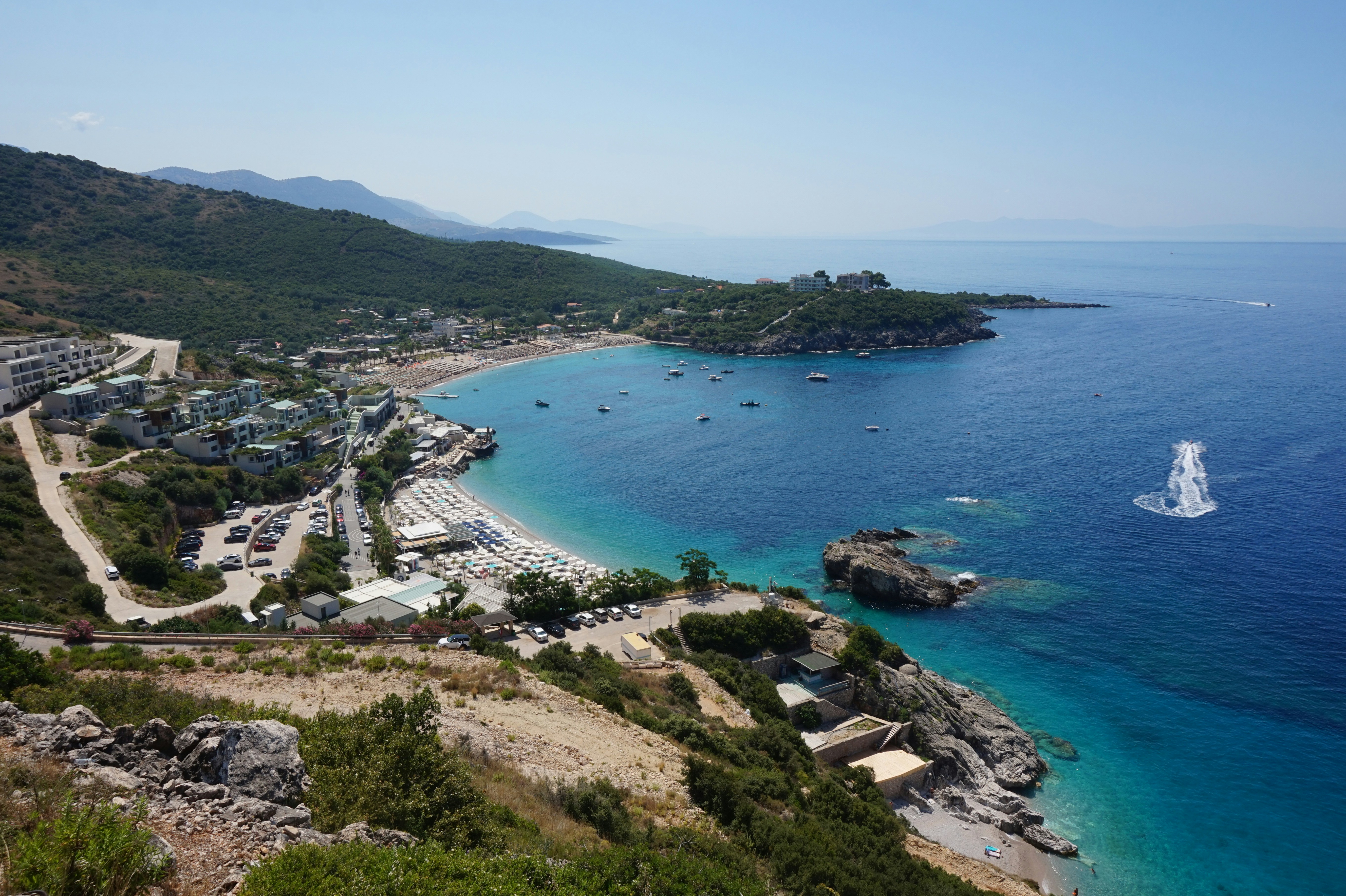 Aerial view of Jale bay showing beach development, umbrellas, and boats along the Albanian Riviera coastline