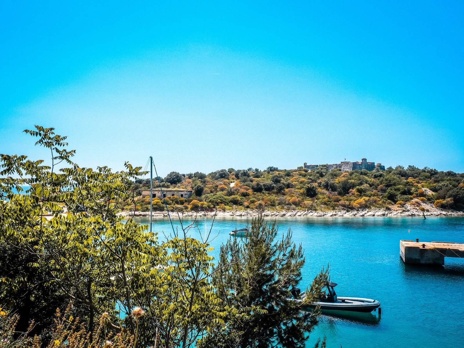 Porto Palermo castle on its peninsula with turquoise bay water and surrounding green hills