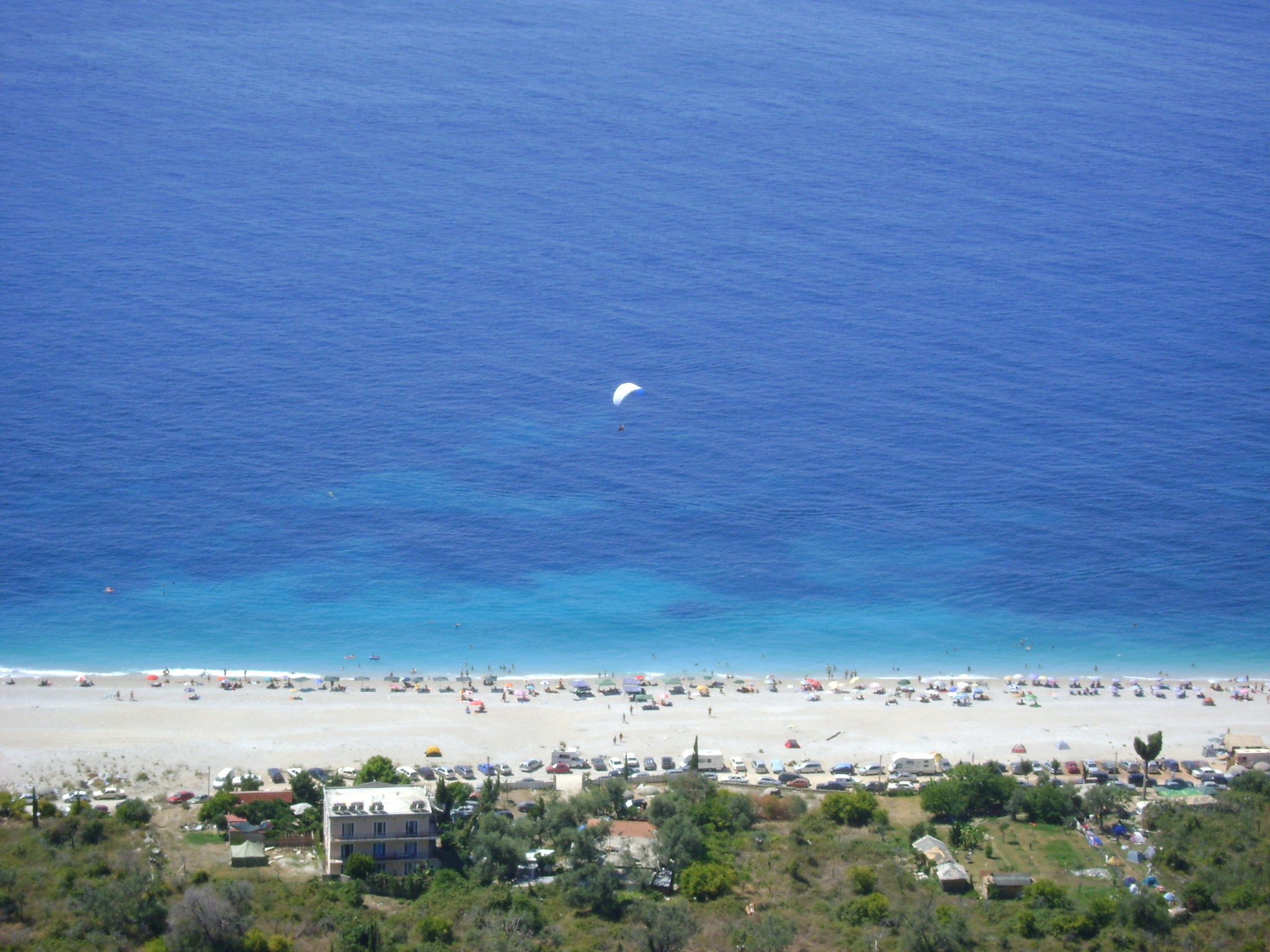 Dhermi coastline with white pebble beaches and turquoise Ionian water backed by the Ceraunian Mountains