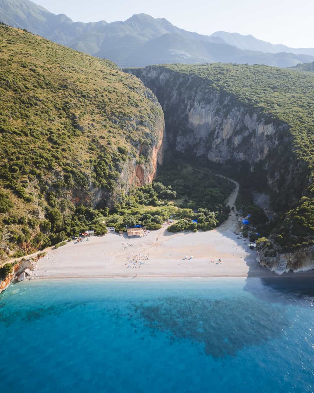 Canyon trail descending toward a secluded beach cove on the Albanian Riviera