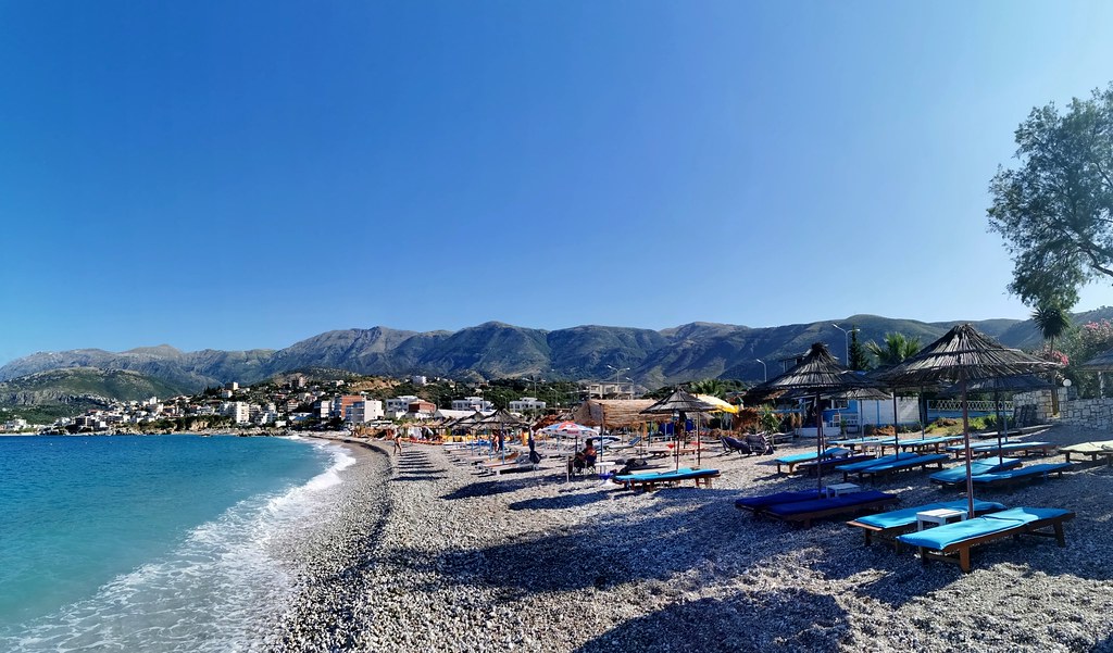 Livadhi Beach with crystal-clear water and beach umbrellas, viewed from the sea