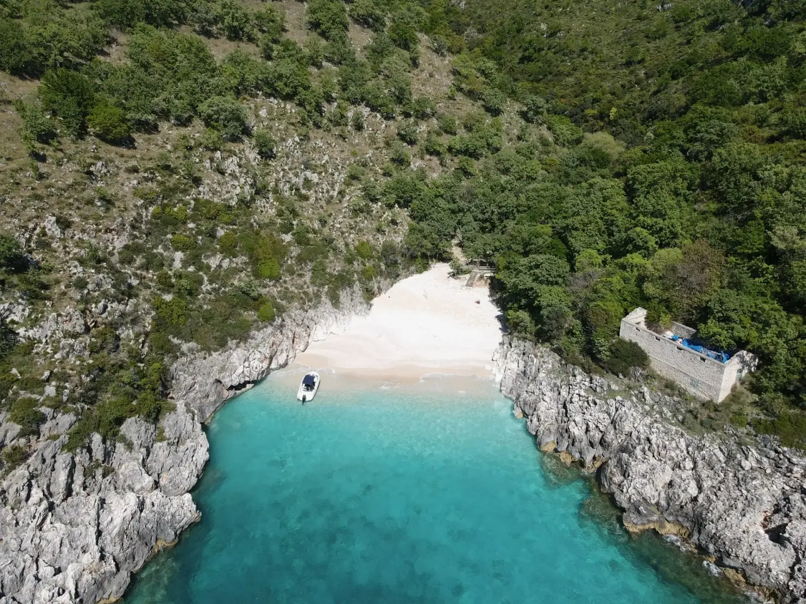 Aerial view of a tiny boat-access cove on the Albanian Riviera, similar to Goats Bay