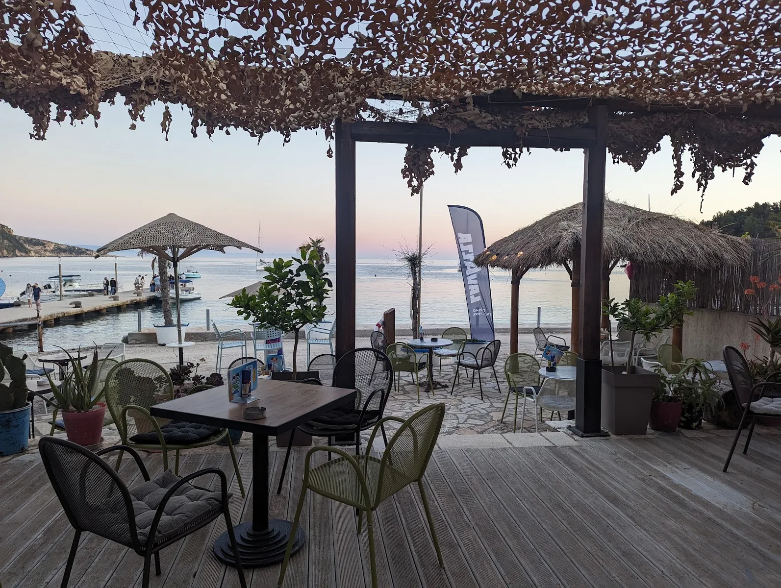 Sunset view of the Ionian sea from Manolo Beach Bar's wooden deck on Spile promenade