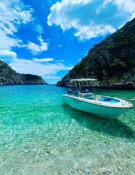 Speedboat anchored off a cliff-backed cove on a Himara Seas the Day cave-and-beach tour, Albanian Riviera
