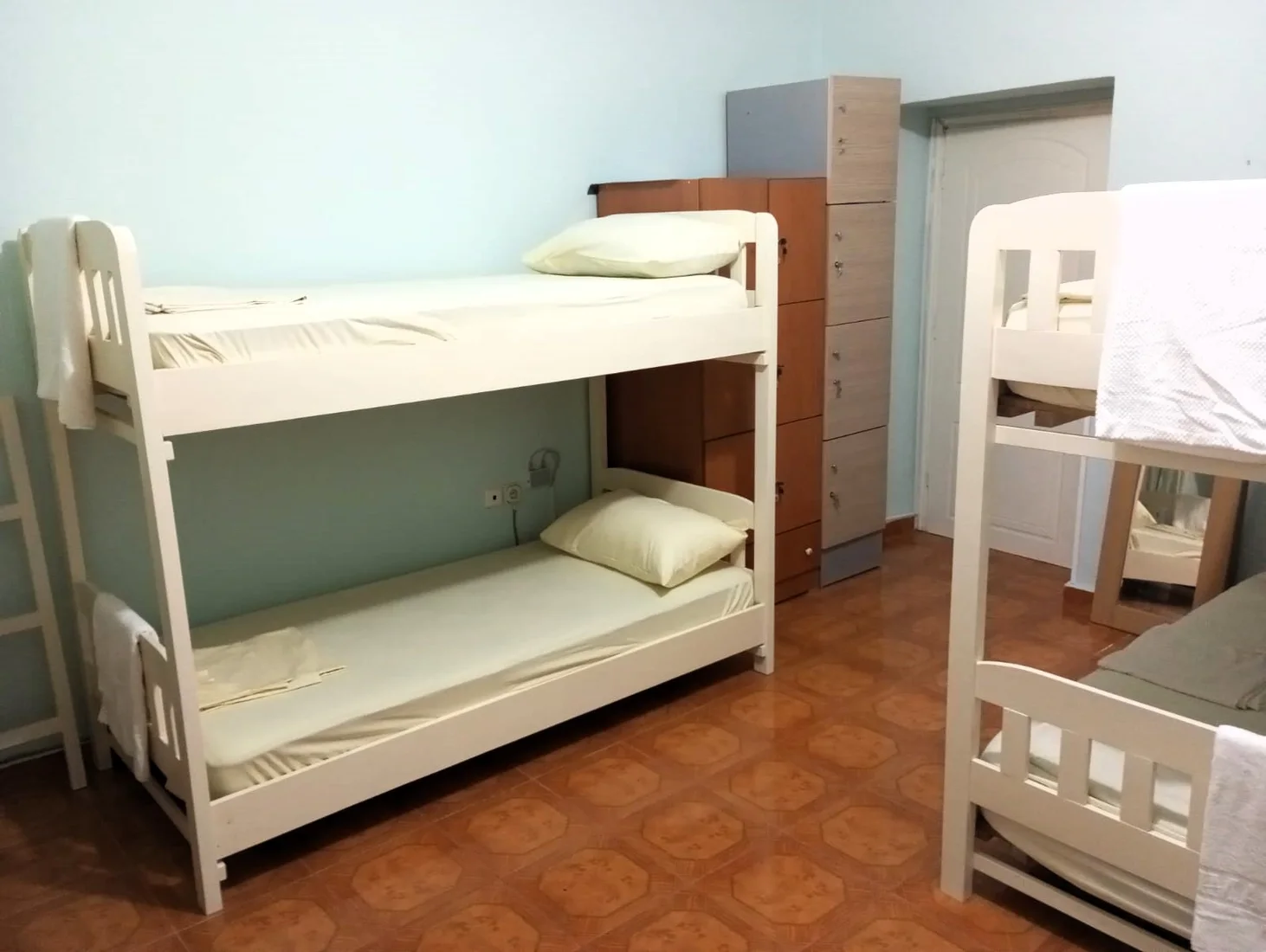 Bright dormitory with bunk beds and lockers at Natural Hostel in Himara