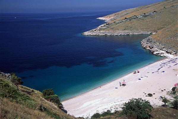 Llamani Beach with deep turquoise water in a secluded bay surrounded by rocky cliffs